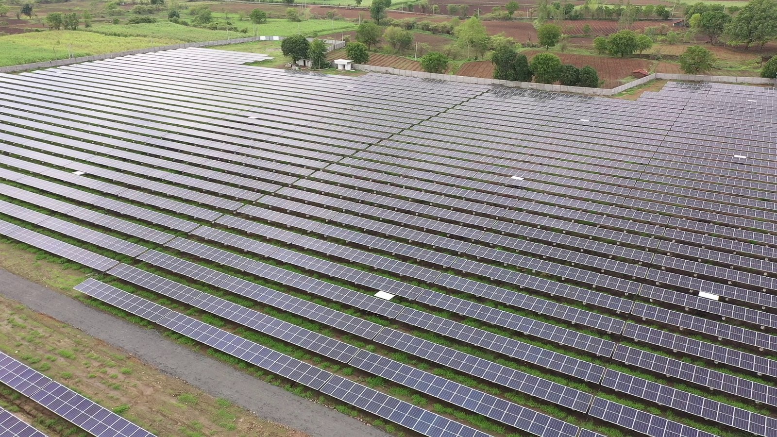 Ground-mounted solar panels at Rayzon Solar Park 6 in Goddha spread across open fields.